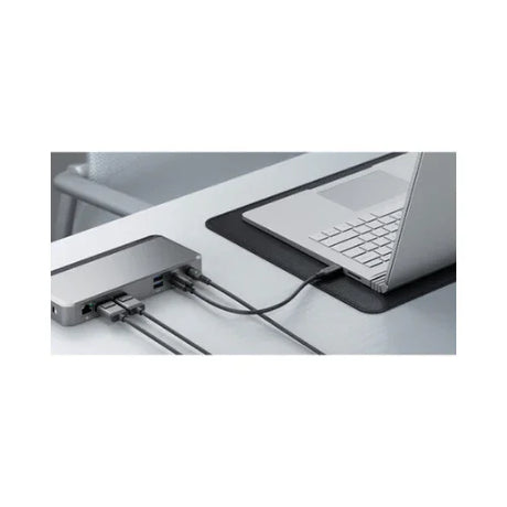 A silver laptop sits on a gray desk atop a black mat, connected with multiple cables to the ALOGIC Alogic DX2 USB-C 4K Display 65W PD Universal Dock | Adapter Included, creating an organized and modern workspace.