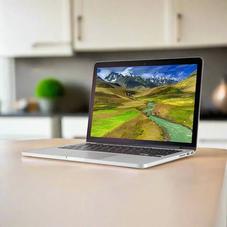A silver Apple MacBook Pro 2015 A1502 i5 5257U 2.7GHz 8GB 256GB SSD 13.3" by Apple sits on a light kitchen table, its Retina Display showing green hills, a winding river, and snow-capped mountains.