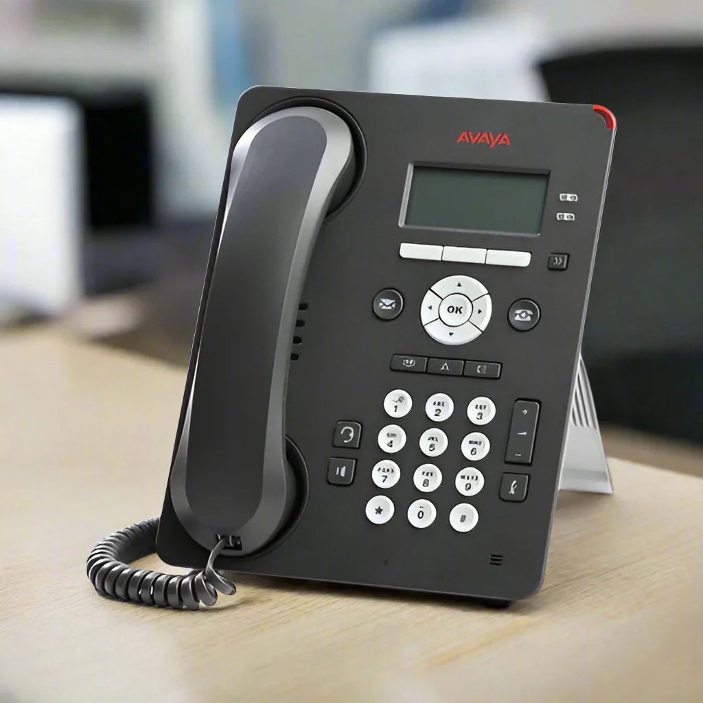 A certified refurbished Avaya 9608G IP Telephone (Part ID: 700419195) with handset and stand by Avaya sits on a light wooden surface. It features a digital display, keypad, and coiled cord—ideal for upgrading your office communications.