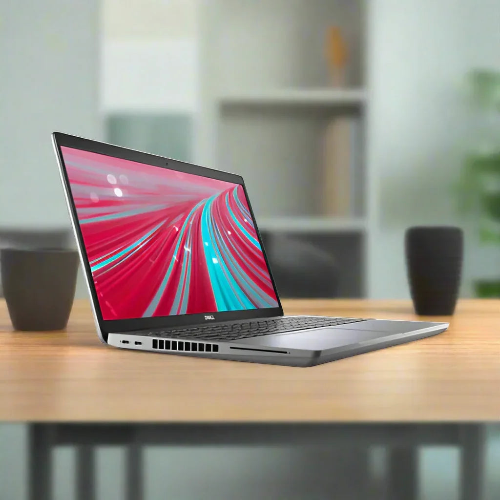 A refurbished Dell Latitude 5521 with an 11th Gen Intel Core i7-11850H, 32GB RAM, and 2TB SSD sits on a wooden table, displaying a vibrant abstract screen. Black cups and blurred shelves with a plant are in the background.