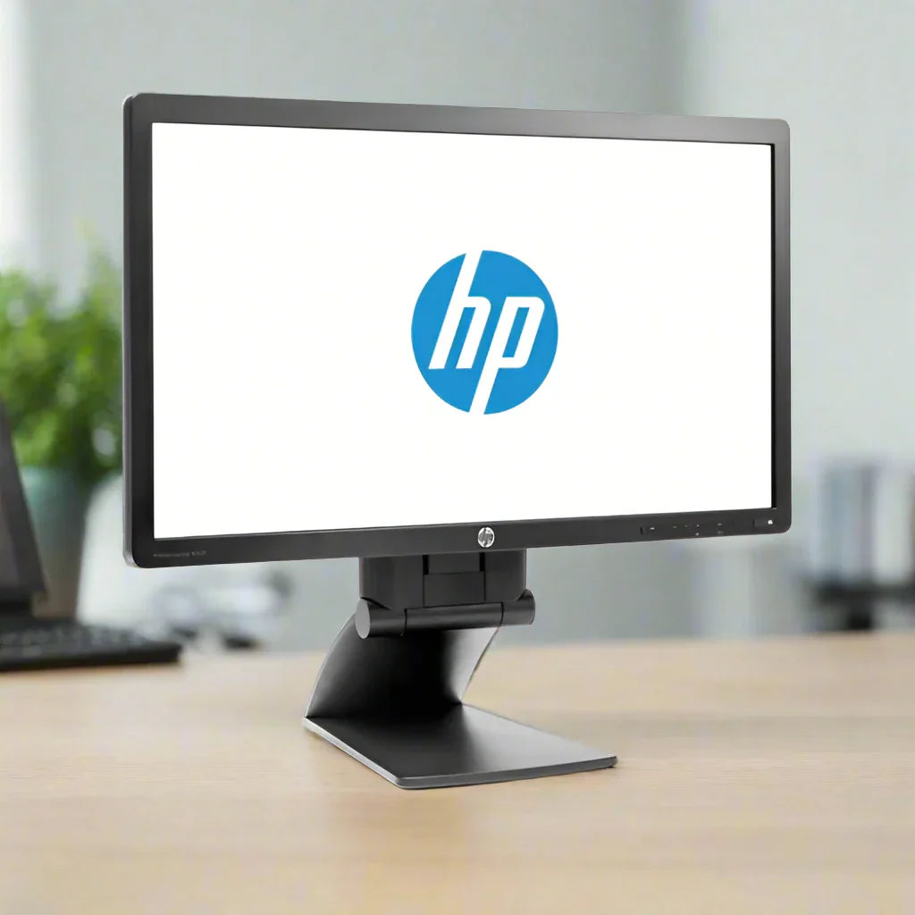 A refurbished HP EliteDisplay E221 21.5" 1920x1080 monitor with the HP logo on screen sits on a wooden desk in a modern office, with a blurred background featuring a plant and office items.