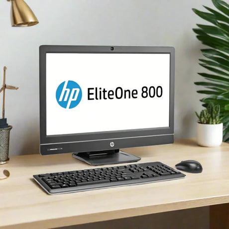 An HP EliteOne 800 G1 AIO i7 desktop with 8GB RAM, 1TB HDD, and a 23 display sits on a light wood desk with keyboard and mouse. The HP logo is on screen; plants and office supplies are in the background.