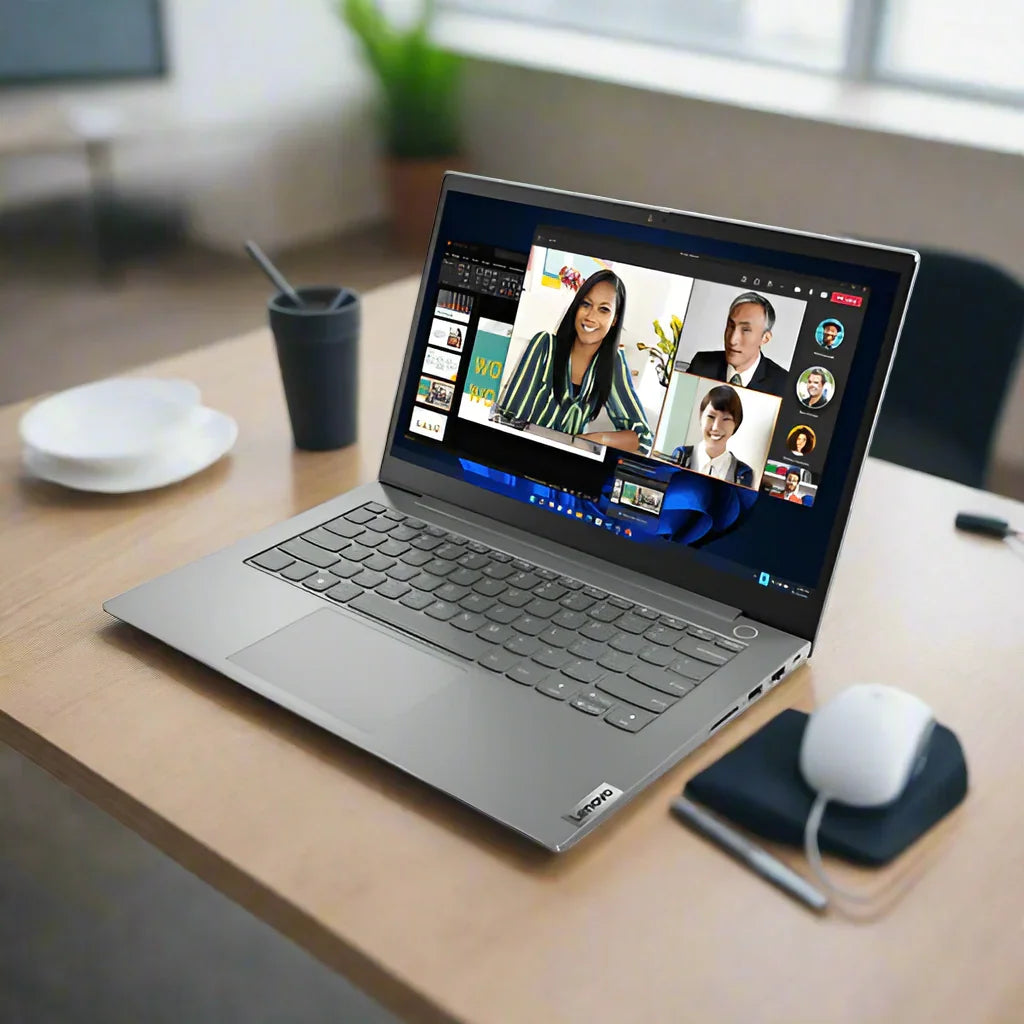 A silver Lenovo ThinkBook 14 G4 i5 1235U laptop is open on a white background, showing a video call with four participants and app windows—ideal for productivity in any workspace.