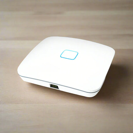 The Open Mesh A62 Tri-Band WiFi Access Point 802.11ac | Wty by Open Mesh, a white enterprise device with a glowing blue square indicator on top and one visible Ethernet port, sits on a light wooden surface.