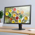 A Lenovo ThinkVision T2324p 23 IPS Monitor (1920x1080, HDMI/DVI/VGA/USB, no stand) sits on a light wooden desk displaying vibrant paint pots; a plant and mouse add to the creative workspace.