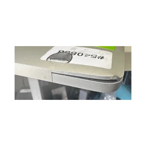 A close-up of the Apple MacBook Pro Mid 2017 A1707 (i7, 16GB, 512GB, 15.4") shows a corner dent with bent casing and slight separation. Part of a label with numbers and barcode is visible on the surface.