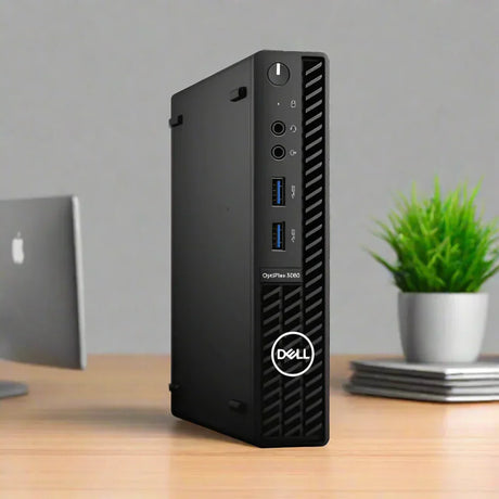 A black Dell OptiPlex 3080 USDT i5 10500T (16GB RAM, 256GB SSD, Windows 11 Pro) sits on a wooden desk beside a green potted plant, notebooks, and a monitor in a modern office setting.