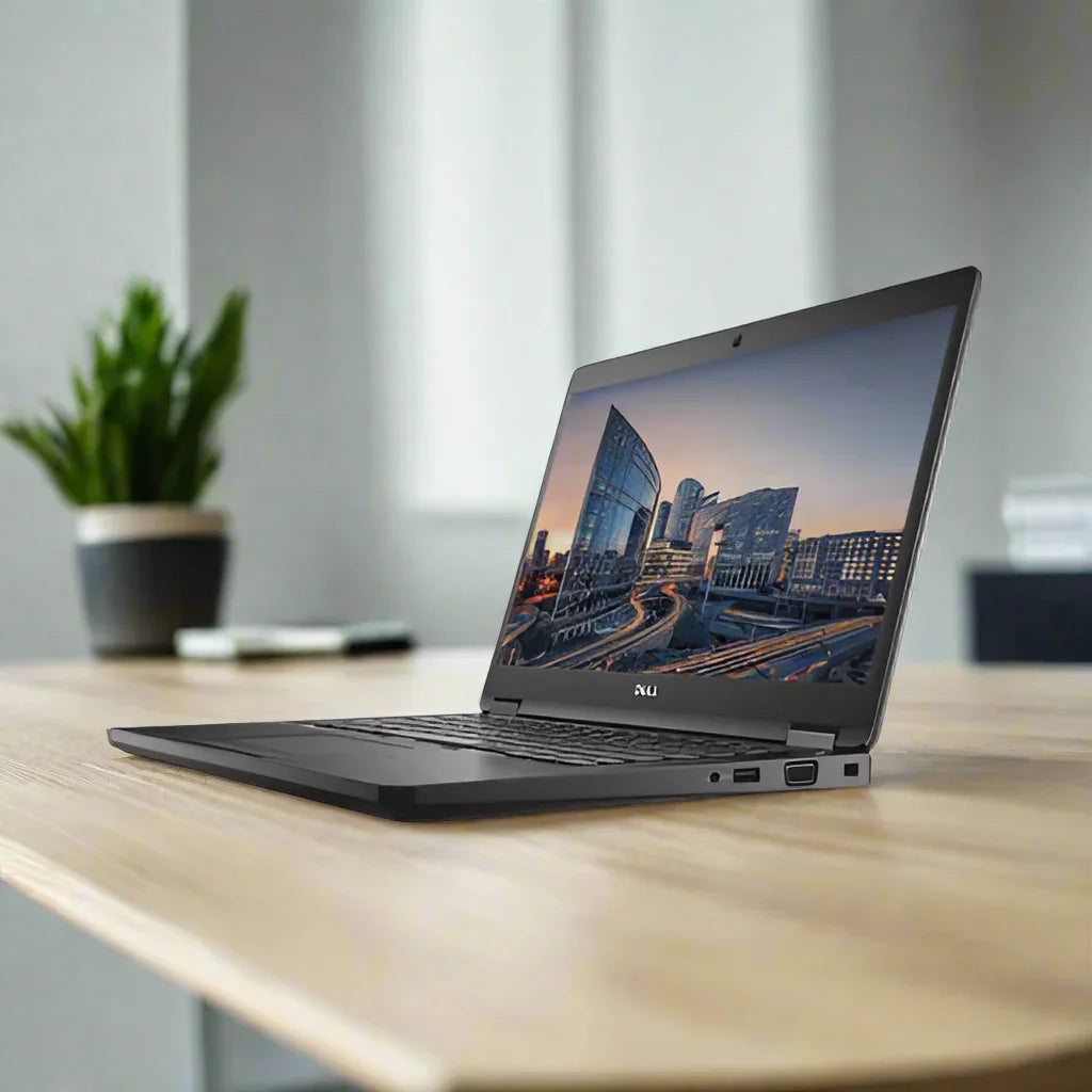 A refurbished Dell Latitude 14 5480 with an Intel i5-6200U, 8GB RAM, and 256GB SSD sits open on a wooden desk showing a cityscape, with a green potted plant and white wall blurred in the background.