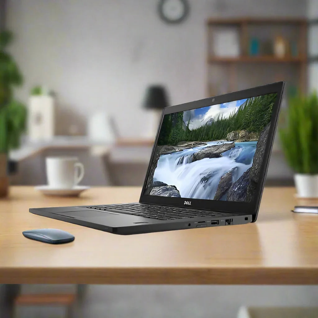 A certified refurbished Dell Latitude 7490 i5-8350U 1.7GHz 8GB 128GB SSD 14" HD W11P laptop sits on a wooden desk beside a wireless mouse in a modern, blurred office with shelves, cups, and a clock.