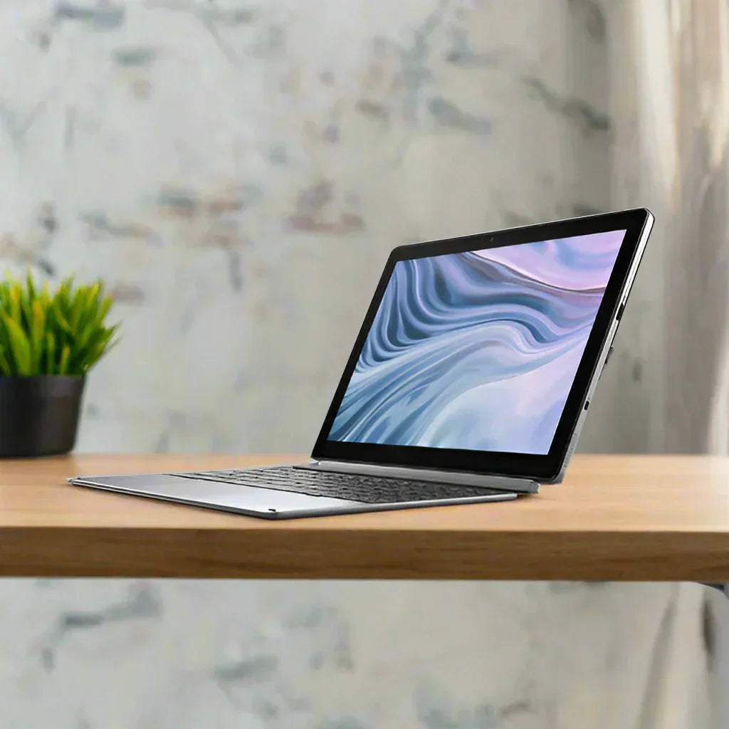 A slim Dell Latitude 7210 2-in-1 i7 laptop with a blue and white screen sits open on a wooden desk, while a small green potted plant is seen in the background against a light, textured wall.