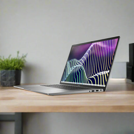 A certified refurbished Dell Latitude 7640 i7-1370P (5.2GHz, 32GB RAM, 1TB SSD, 16" FHD+, Windows 11 Pro) sits open on a wooden desk showing a colorful abstract display, with a green plant in a black pot nearby against a beige wall.