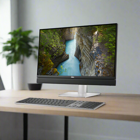 A Dell Refurbished OptiPlex 7410 AIO with an i5-13500T, 16GB RAM, 512GB SSD, WiFi, and a 24.6 display shows a scenic canyon on a wooden desk with a wireless keyboard in a minimalist modern office.