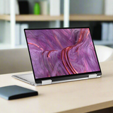 A silver Dell Refurbished XPS 9310 2-in-1 i7 laptop in tent mode showcases a vibrant abstract display with swirling pink and purple on its 13.4 touchscreen.