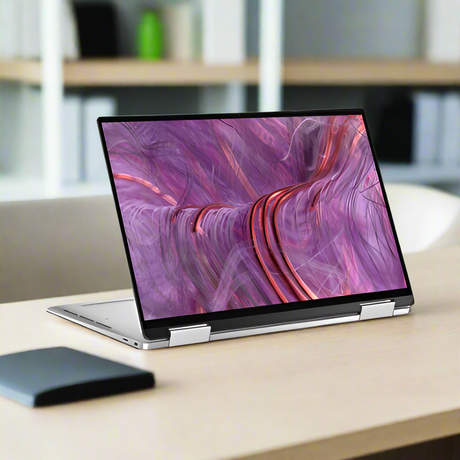 A silver Dell Refurbished XPS 9310 2-in-1 i7 laptop in tent mode showcases a vibrant abstract display with swirling pink and purple on its 13.4 touchscreen.