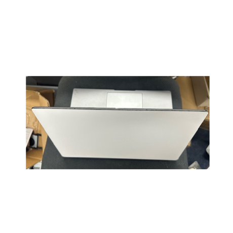 A silver Dell Latitude 5430 Laptop 14" Core i5 16GB 256GB Touch Win 11 Pro + Skin by Dell sits partially closed on a black fabric surface, surrounded by cardboard boxes and other items, seen from above.