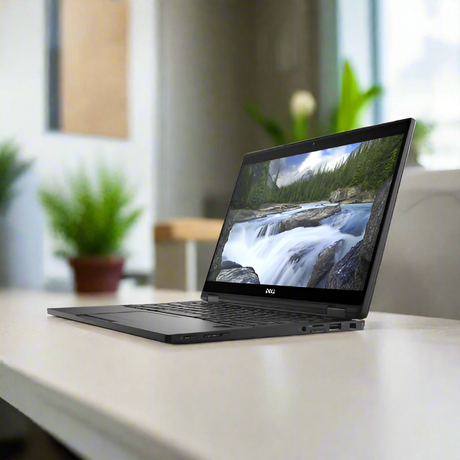 A certified refurbished Dell Latitude 7389 2-in-1 i5 7300U laptop is open on a light desk, displaying a scenic river. Potted green plants brighten the softly blurred room in the background.