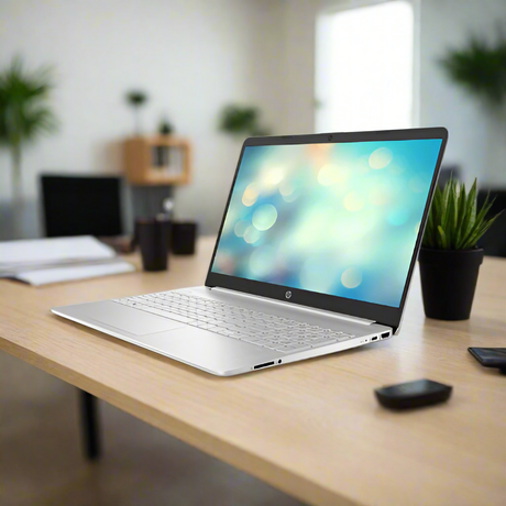 A certified refurbished HP 15S-EQ3XXX laptop (Ryzen 5 5625U, 16GB RAM, 512GB SSD, 15.6" W11P) sits on a wooden desk in a modern office, surrounded by a potted plant, smartphone, and supplies with shelves and plants behind.