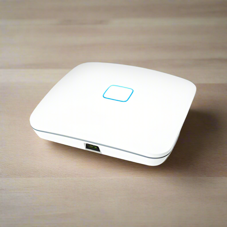 The Open Mesh A62 Tri-Band WiFi Access Point 802.11ac | Wty by Open Mesh, a white enterprise device with a glowing blue square indicator on top and one visible Ethernet port, sits on a light wooden surface.