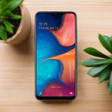A refurbished Samsung Galaxy A20 SM-A205YN 32GB in Blue displays a vivid abstract wallpaper, showing 12:45 and Friday, February 22, with thin bezels and a small top notch. This unlocked smartphone is by Samsung.