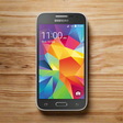 A Samsung SM-G360G Galaxy Core Prime 8GB Unlocked 4G LTE Dual SIM Android from Samsung, displaying a colorful geometric wallpaper with the time 11:00 AM and date Monday, September 15, rests on a wooden surface.