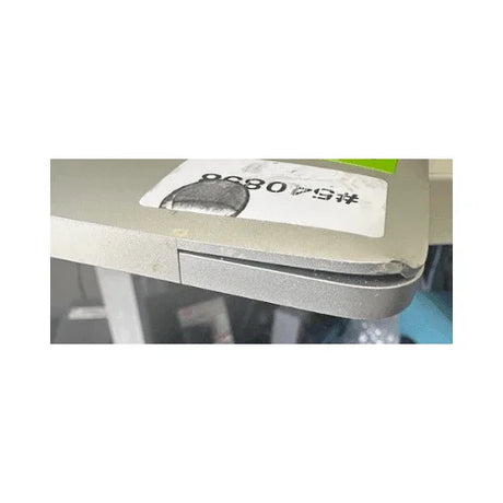 A close-up of the Apple MacBook Pro Mid 2017 A1707 (i7, 16GB, 512GB, 15.4") shows a corner dent with bent casing and slight separation. Part of a label with numbers and barcode is visible on the surface.
