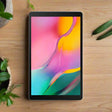 A 10.1-inch Samsung Galaxy TAB A SM-T510 Black 32GB tablet with a vivid screen rests on a wooden surface among potted plants, highlighting the sleek, certified refurbished design and expandable storage. Includes 3-month warranty.